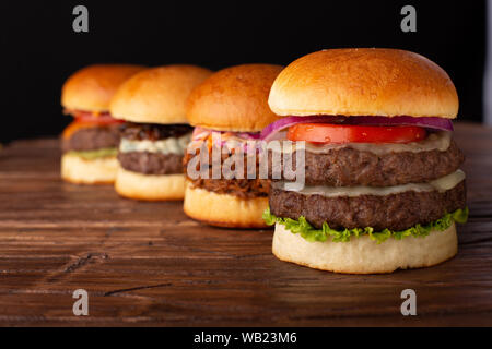 Quattro diversi hamburger in una riga posta su un tavolo di legno Foto Stock