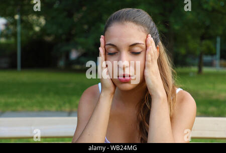 Giovane donna soffre di mal di testa all'esterno. Foto Stock