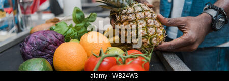 Panoramica dell African American uomo con ananas vicino al supermercato counter Foto Stock