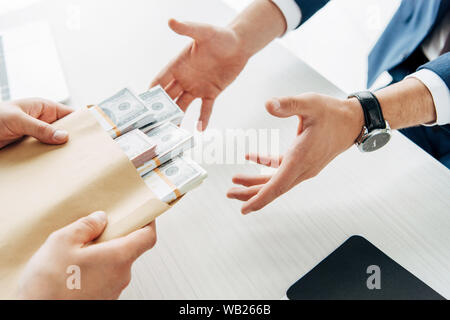 Vista ritagliata dell'uomo dare tangenti al business partner mentre si stringono le mani isolato su bianco Foto Stock