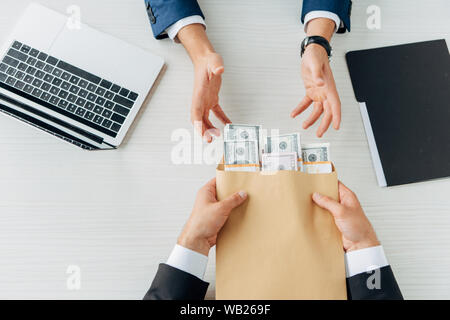 Vista ritagliata dell'uomo dare tangenti al business partner e stringono le mani su bianco Foto Stock