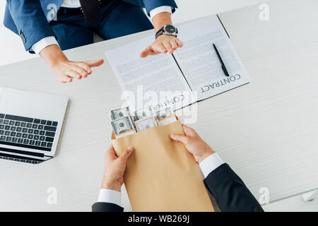 Vista ritagliata di imprenditore dando tangente al business partner e stringono le mani su bianco Foto Stock