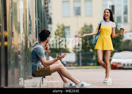 Uomo e donna asiatica sorridente e azienda bicchieri di carta Foto Stock