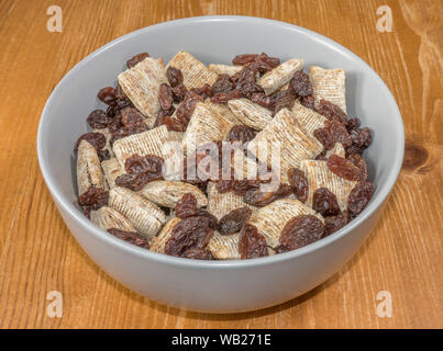 Chiudere POV overhead shot di uvetta miscelati a secco con frumento Cereali per la colazione in una ciotola. Foto Stock