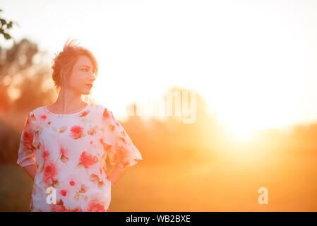 Giovane donna in camicia floreale in presenza di luce solare Foto Stock