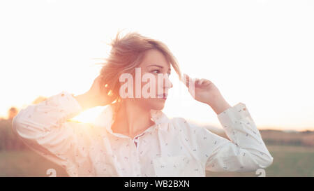 Giovane donna in maglia bianca e trucco unico in presenza di luce solare Foto Stock