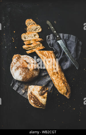 Piatto di laici baguette a fette e focaccia su sfondo nero Foto Stock
