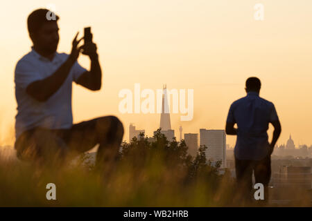 Londra, Regno Unito. 23 Agosto, 2019. Regno Unito: meteo locali e turisti di godere di un caldo tramonto dalla cima del Greenwich Park. Credito: Guy Corbishley/Alamy Live News Foto Stock