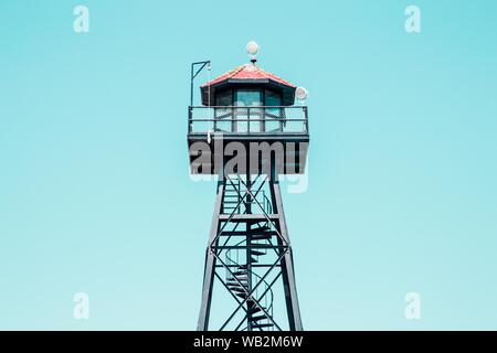 Foto ad angolo basso di una torre nera bagnino con rosso tetto Foto Stock