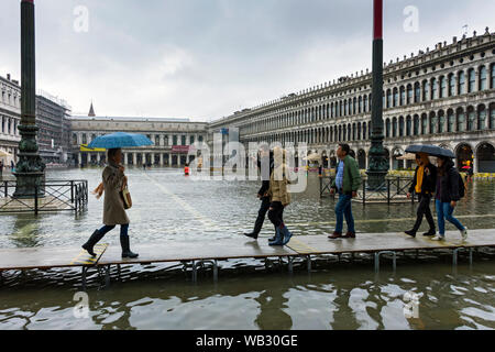 La gente camminare su piattaforme elevate durante un'acqua alta alta (acqua), eventi di Piazza San Marco, Venezia, Italia Foto Stock