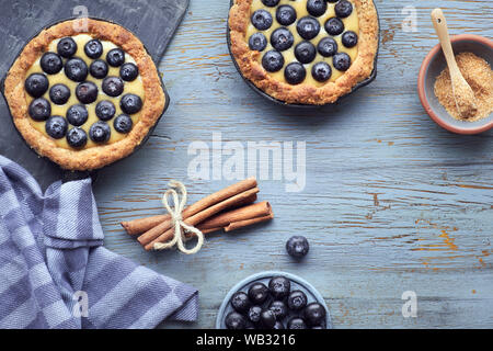 Piatto di laici mirtillo deliziosi pasticcini con crema alla vaniglia crema sulla luce di legno rustico sfondo. Vista da sopra con copy-spazio. Foto Stock
