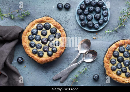 Piatto di laici mirtillo deliziosi pasticcini con vaniglia e crema pasticcera, vista dall'alto sulla luce rustico sfondo di legno Foto Stock