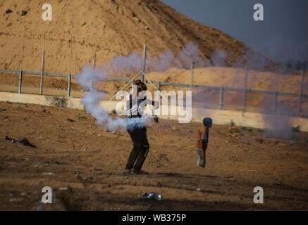 La striscia di Gaza, la Palestina. 23 Ago, 2019. Un dimostrante palestinese getta indietro una lacrima bombola del gas verso le forze di Israele durante un anti-Israele dimostrazione presso il Israel-Gaza recinzione di confine nel sud della striscia di Gaza. Credito: SOPA Immagini limitata/Alamy Live News Foto Stock