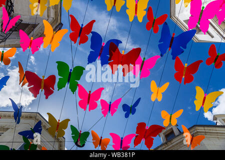 Multi-colorato decorativo in plastica cut-out farfalle al di sopra di una strada pedonale - Chatellerault, Vienne, in Francia. Foto Stock