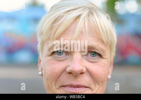 Close-up verticale di una serena senior donna sorridente mentre guardando la telecamera con i suoi bellissimi occhi blu Foto Stock