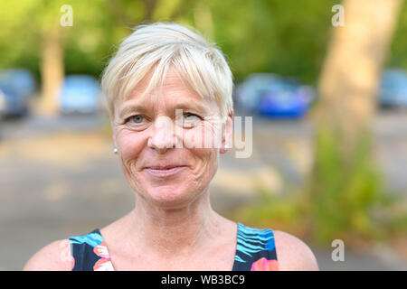 Ritratto di un vecchio attraente bionda donna sorridente all'aperto in un parco pubblico Foto Stock