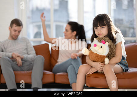 Triste figlia bambino giocattolo di contenimento sentendosi ferita circa i genitori sostenendo Foto Stock