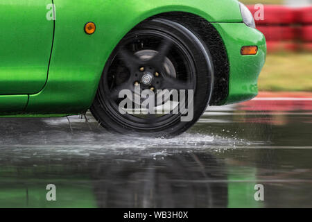 Auto sportiva guidato su strade piovose close up su una ruota con motion blur effetto Foto Stock