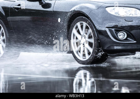 Auto sportiva guidato su strade piovose close up su una ruota con motion blur effetto Foto Stock