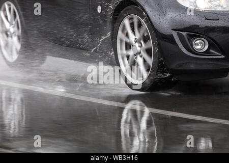 Auto sportiva guidato su strade piovose close up su una ruota con motion blur effetto Foto Stock