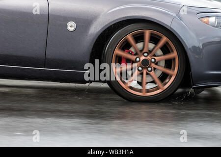 Auto sportiva guidato su strade piovose close up su una ruota con motion blur effetto Foto Stock