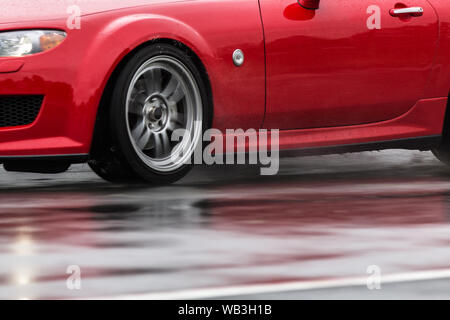 Auto sportiva guidato su strade piovose close up su una ruota con motion blur effetto Foto Stock