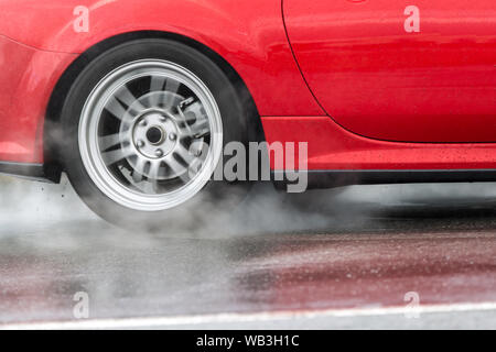 Auto sportiva guidato su strade piovose close up su una ruota con motion blur effetto Foto Stock