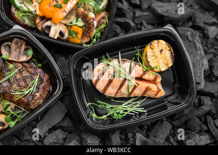 Set di cibo alla griglia a passare scatole nere sul carbone Foto Stock