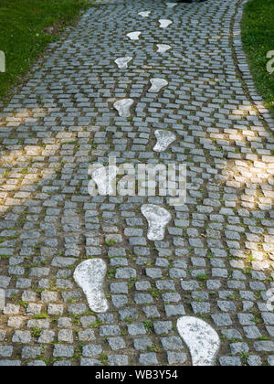 Dipinto di bianco di impronte su un sentiero acciottolato che conduce verso l'alto Foto Stock