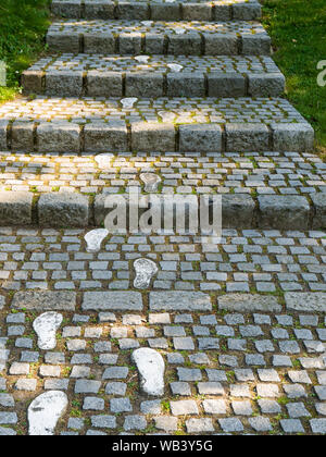 Dipinto di bianco di impronte su un sentiero acciottolato che conduce verso l'alto Foto Stock