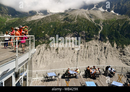 I turisti sulle terrazze del Montenvers stazione ferroviaria con le Aiguilles du Dru, una montagna del massiccio del Monte Bianco, Chamonix, alpi, Francia Foto Stock