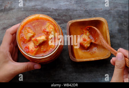 cibo speziato per vegan, tofu formaggio da tofu fermentato, salsa popolare per pasto, cagliata di fagioli fermentata in vaso, donna mano portarlo in ciotola di legno da cucchiaio Foto Stock