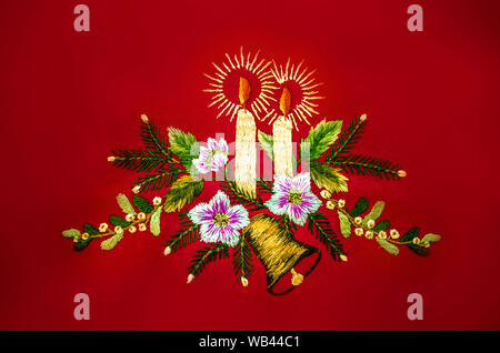 Natale con le candele accese,bell e fiori,ricamato maglia satinata su sfondo rosso Foto Stock