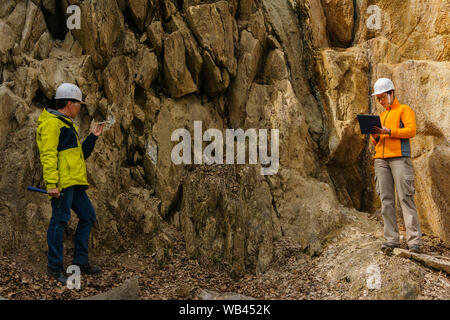 Maschio e femmina di geologi prende un campione del minerale e registrare i dati in un canyon Foto Stock