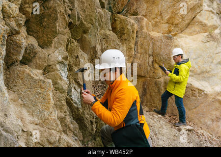 Maschio e femmina di geologi prende un campione del minerale e registrare i dati in un canyon Foto Stock