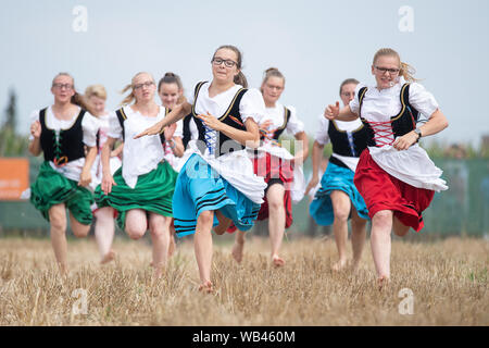 Markgröningen, Germania. 24 agosto 2019, 24 agosto 2019, Baden-Wuerttemberg, Markgröningen: Pastore ragazze correre su un campo di stoppie durante il Markgröninger Schäferlauf. Sophia Hagenlocher (M) ha vinto la Schäferlauf. Foto: Sebastian Gollnow/dpa Credito: dpa picture alliance/Alamy Live News Foto Stock