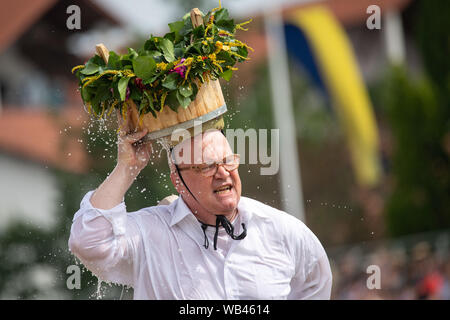 Markgröningen, Germania. 24 agosto 2019, 24 agosto 2019, Baden-Wuerttemberg, Markgröningen: ZDF presenter Achim inverno viene eseguito durante la Markgröninger Schäferlauf con un secchio di acqua sulla sua testa. Foto: Sebastian Gollnow/dpa Credito: dpa picture alliance/Alamy Live News Foto Stock