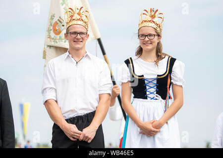 Markgröningen, Germania. 24 agosto 2019, 24 agosto 2019, Baden-Wuerttemberg, Markgröningen: Pastore re Dominik Fröschle e pastore regina Sofia Hagenlocher stand su un podio durante il Markgröninger Schäferlauf. Foto: Sebastian Gollnow/dpa Credito: dpa picture alliance/Alamy Live News Foto Stock