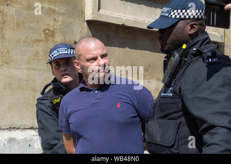 Portland Place, Londra, Regno Unito. 24 agosto 2019. Un uomo con una polo blu è detenuto da due agenti di polizia vicino a un edificio civico in pietra nel centro di Londra. Gli agenti indossano uniformi scure con cappelli a scacchi e telecamere per il corpo. Protesta libera di Tommy Robinson fuori dalla BBC. Allo stesso tempo si sta svolgendo una contromanifestazione, organizzata da Stand Up to razzism and Unite Against fascism. Penelope Barritt/Alamy Live News Foto Stock