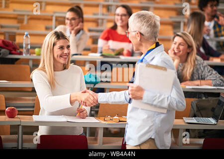 Sorridente studente riceve un esame di successo in una classe Foto Stock