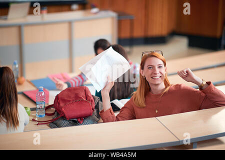 Felice ragazza mostra exam carta con un plus in classe Foto Stock