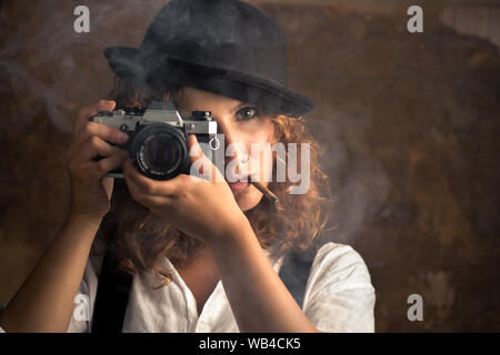 Donna fotografo con Bowler e bretelle di fumare un sigaro Foto Stock