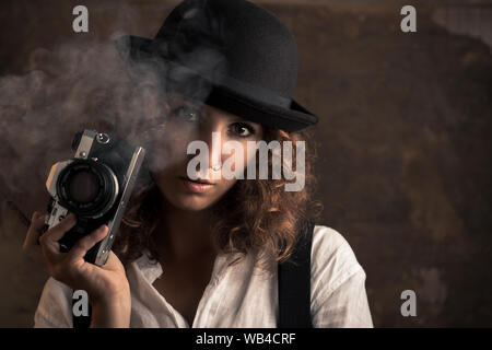 Donna fotografo con Bowler e Giarrettiere tenendo un sigaro Foto Stock