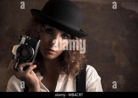 Donna fotografo con Bowler e Giarrettiere tenendo una fotocamera Foto Stock