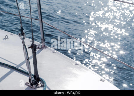 Sfondo - yachting. frammento dello scafo di una barca a vela con manovre contro lo sfondo di acqua con Sun mette in evidenza Foto Stock