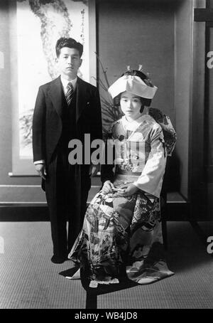 [ 1930 Giappone - Sposa e lo Sposo ] - Dal 1920s, matrimonio giapponese dogana ha subito una grande trasformazione a causa di influenze occidentali. Ciò è visibile in questo bellissimo ritratto di nozze in cui lo sposo indossa una tuta occidentale, mentre la sposa è rivestita di un meravigliosamente decorate wedding kimono. Xx secolo gelatina vintage silver stampa. Foto Stock