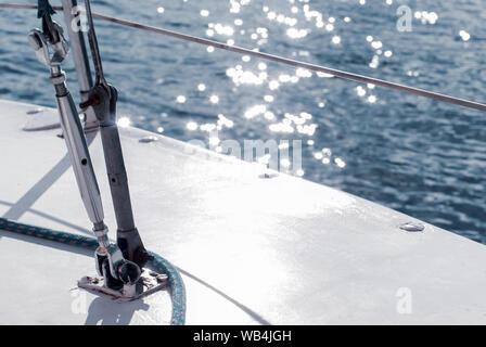 Sfondo - yachting. frammento dello scafo di una barca a vela con manovre contro lo sfondo di acqua con Sun mette in evidenza Foto Stock