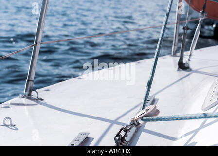 Sfondo - yachting. frammento dello scafo di una barca a vela con manovre contro lo sfondo di acqua con Sun mette in evidenza Foto Stock