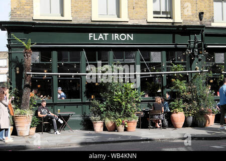 Ferro piatto di pub e la gente di turisti in estate su strada commerciale in Spitalfields East London E1 Inghilterra UK KATHY DEWITT Foto Stock