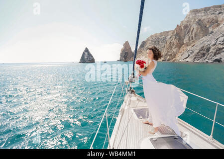Bianco con yacht a vela va impostata lungo l'isola in una giornata calda. Il mare blu, blu cielo. La Crimea. a bordo di una giovane coppia in amore. la sposa e lo sposo. weddin Foto Stock
